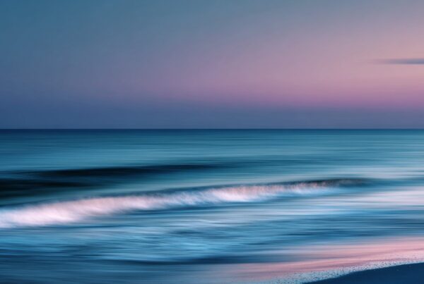 Soft, blurred waves roll across a pastel-colored shoreline at sunset, symbolizing the flow and serenity often associated with the question—what is tantra sex.