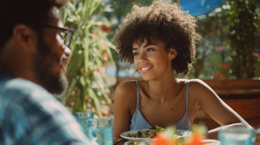 A smiling woman enjoying a meal with her partner at an outdoor café, capturing connection and curiosity, reflecting what is sexual energy.