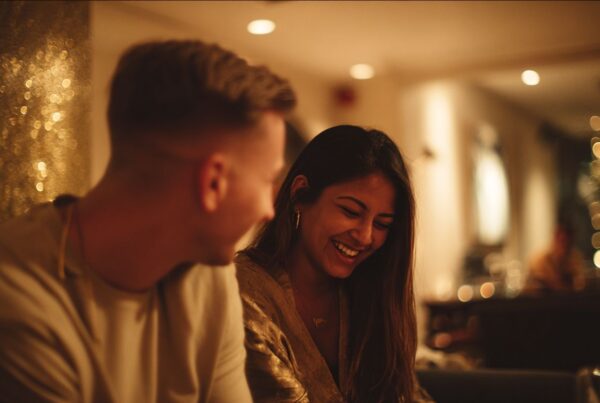 Couple sharing a warm laugh over dinner lights, embodying the relaxed, intimate feel of slow dating in San Francisco.