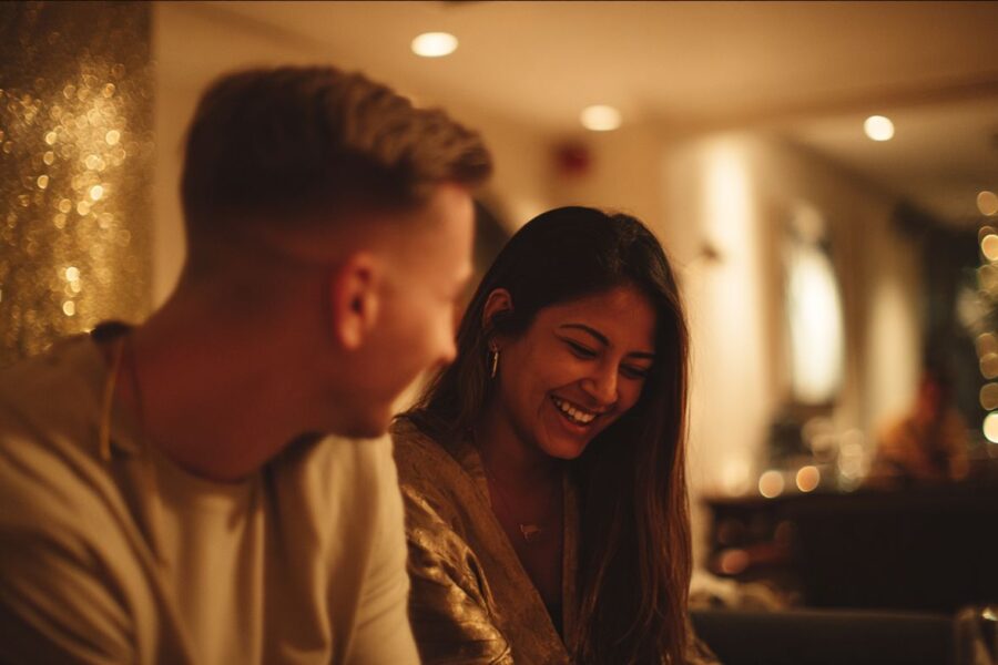 Couple sharing a warm laugh over dinner lights, embodying the relaxed, intimate feel of slow dating in San Francisco.