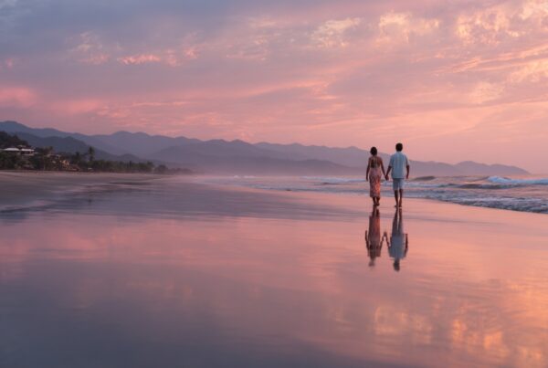 People walking along the beach holding hands after a session at a tantra retreat