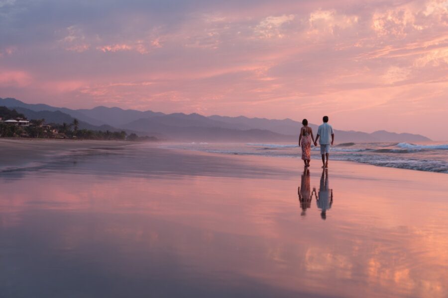 People walking along the beach holding hands after a session at a tantra retreat
