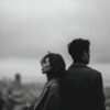 A couple standing back to back overlooking a city, illustrating emotional distance often addressed through tantra for a disconnected relationship.